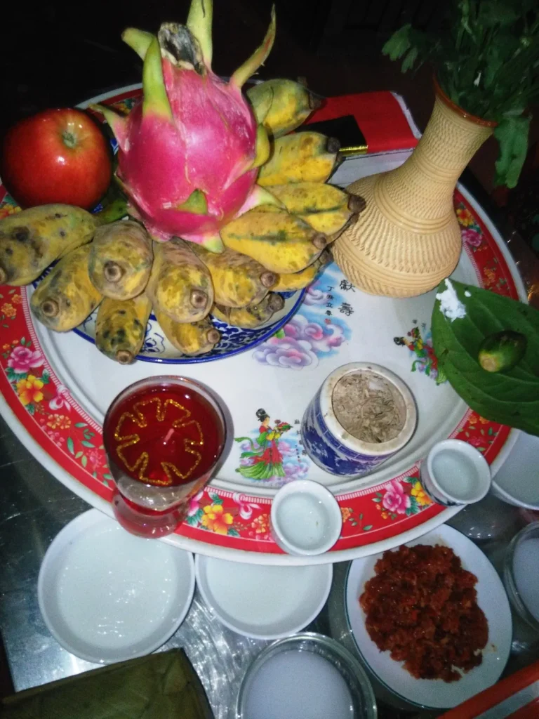Mâm cúng giao thừa ban đêm có thanh long, chuối, táo, trầu cau, nến, bát hương, chén nước và đĩa xôi gấc
