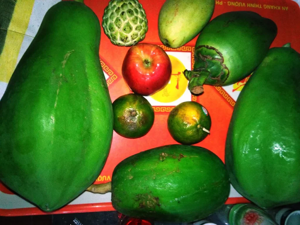 Mâm ngũ quả nhìn từ trên: đu đủ, xoài, mãng cầu, cam và táo đỏ trên khay đỏ